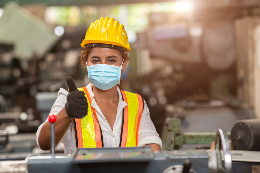 Woman giving thumbs up at manufacturing facility