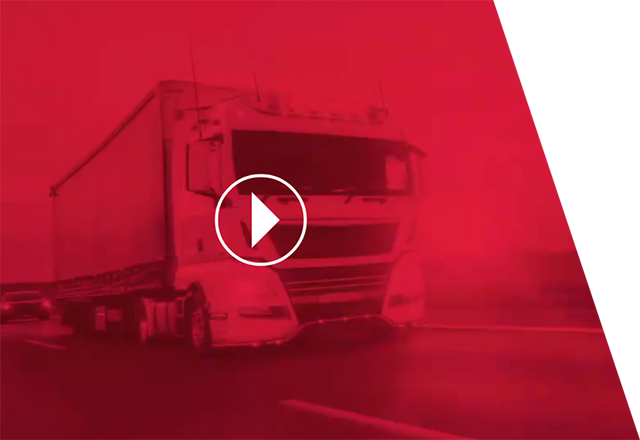 Imagen difuminada de un camión en una carretera bajo luces rojas